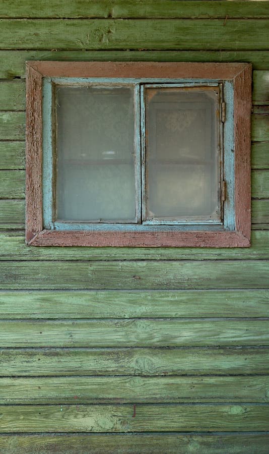 Une petite vieille fenêtre fermée dans le mur en bois rustique vert d'une vieille maison photos stock Une petite vieille fenêtre fermée dans le mur en bois rustique vert d'une vieille maison photos stock