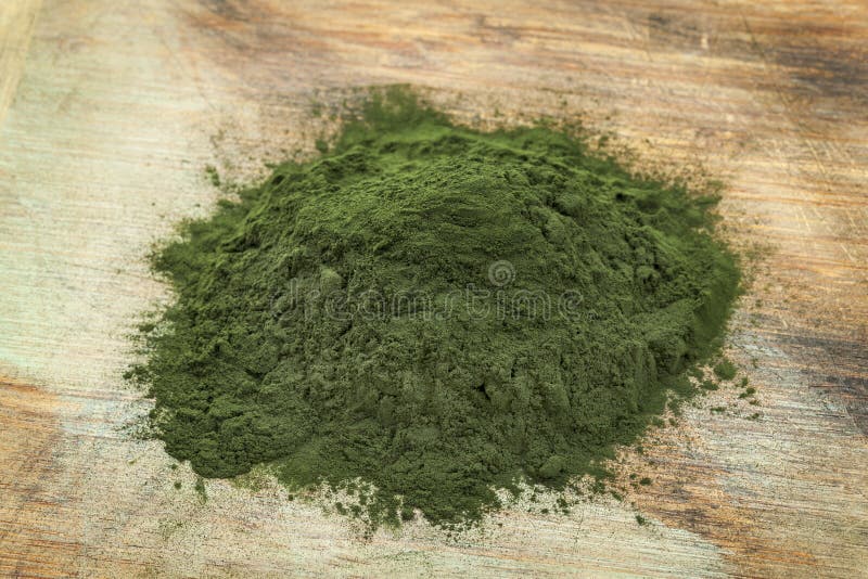 A pile of Hawaiian spirulina powder on wooden surface. A pile of Hawaiian spirulina powder on wooden surface