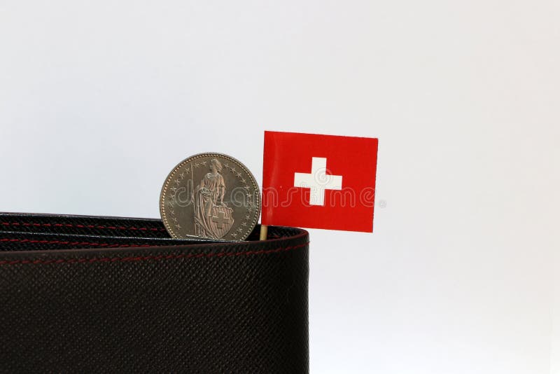 Une pièce de monnaie d'un franc suisse et de mini bâton de drapeau de la Suisse sur le portefeuille noir avec le fond blanc Argen images libres de droits Une pièce de monnaie d'un franc suisse et de mini bâton de drapeau de la Suisse sur le portefeuille noir avec le fond blanc Argen images libres de droits