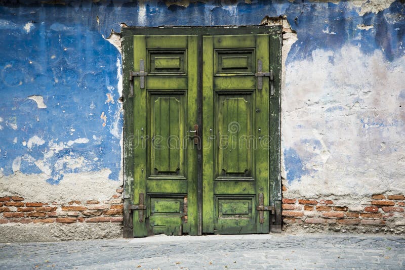 A very old green door and a brick wall destroyed by weather and years ideal for photo sessions background. A very old green door and a brick wall destroyed by weather and years ideal for photo sessions background