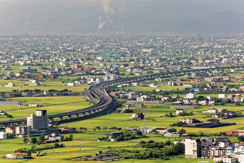 Une route incurv?e par les gisements verts de riz avec des maisons dispers?es dans toute la plaine dans Yilan, Ta?wan photos libres de droits Une route incurv?e par les gisements verts de riz avec des maisons dispers?es dans toute la plaine dans Yilan, Ta?wan photos libres de droits