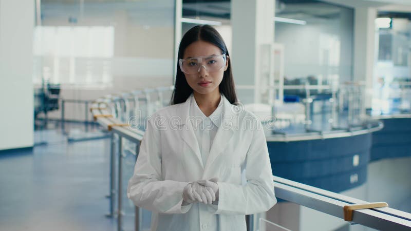Une scientifique asiatique portant des lunettes de protection debout dans un centre scientifique banque de vidéos