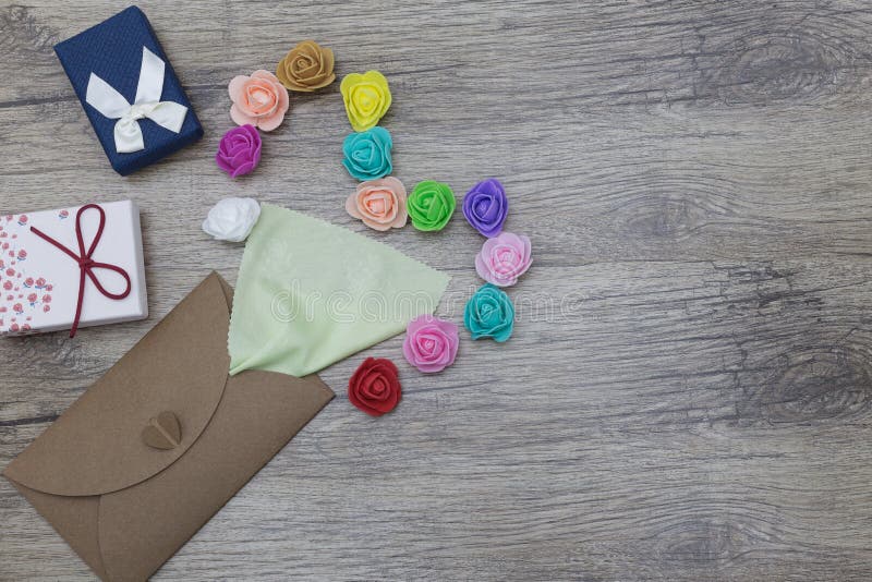 Une serviette vert clair colle hors de l'enveloppe de métier Décoré dans la forme du coeur avec les roses multicolores image plat images libres de droits Une serviette vert clair colle hors de l'enveloppe de métier Décoré dans la forme du coeur avec les roses multicolores image plat images libres de droits