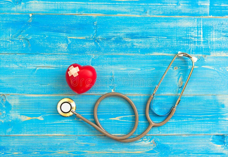 Une seule boule rouge simple d'exercice de main de forme d'amour de coeur avec le backgro en bois bleu de stéthoscope du ` s de m photos stock Une seule boule rouge simple d'exercice de main de forme d'amour de coeur avec le backgro en bois bleu de stéthoscope du ` s de m photos stock