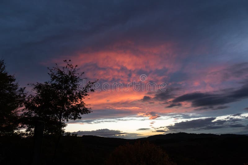 Une silhouette d'arbre et de beaux nuages rouges au coucher du soleil, faisant des formes abstraites photos stock Une silhouette d'arbre et de beaux nuages rouges au coucher du soleil, faisant des formes abstraites photos stock