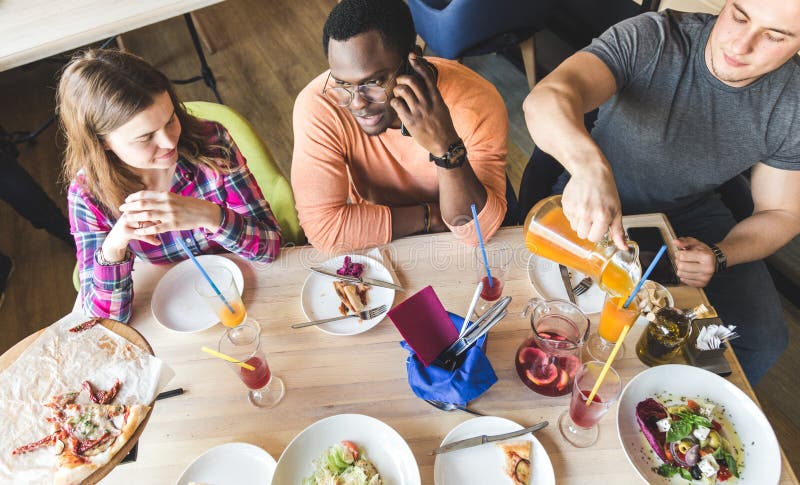 Une soci?t? des jeunes multiculturels dans un caf? mangeant de la pizza, cocktails potables, ayant l'amusement image libre de droits Une soci?t? des jeunes multiculturels dans un caf? mangeant de la pizza, cocktails potables, ayant l'amusement image libre de droits