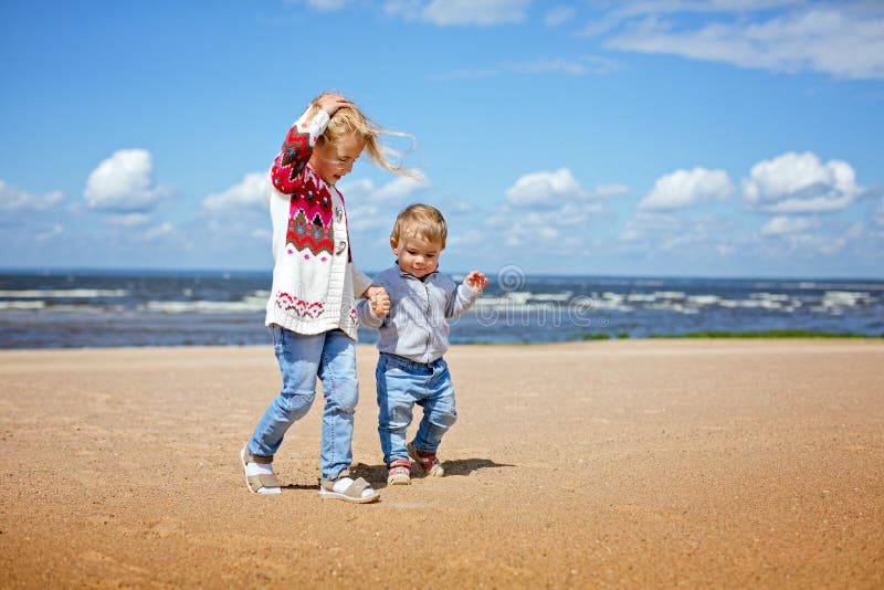 Une soeur et un jeune frère plus âgés Blonds marchent le long de l'être images libres de droits Une soeur et un jeune frère plus âgés Blonds marchent le long de l'être images libres de droits