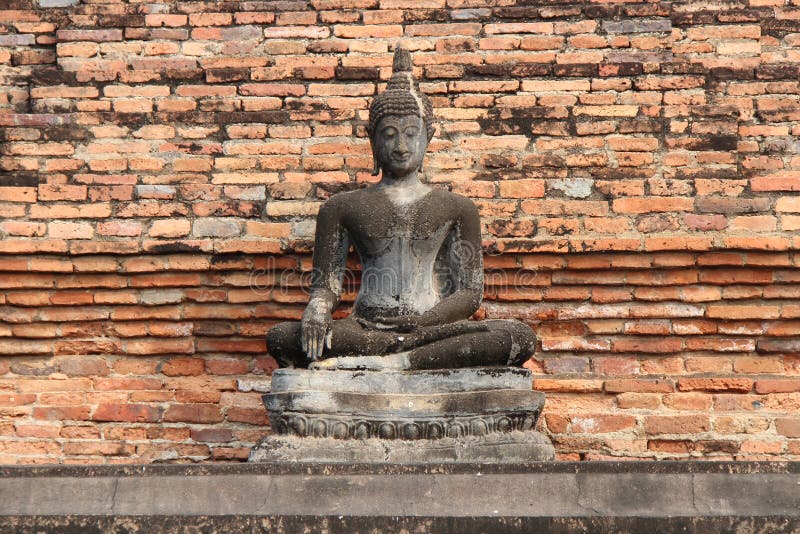 Une statue en pierre de Bouddha a été installée devant un mur de briques dans un parc dans Sukhothai (Thaïlande) photographie stock Une statue en pierre de Bouddha a été installée devant un mur de briques dans un parc dans Sukhothai (Thaïlande) photographie stock