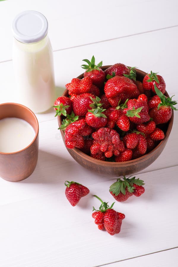 Une tasse avec les fraises fraîches, la tasse et la bouteille en verre de lait s photo libre de droits Une tasse avec les fraises fraîches, la tasse et la bouteille en verre de lait s photo libre de droits