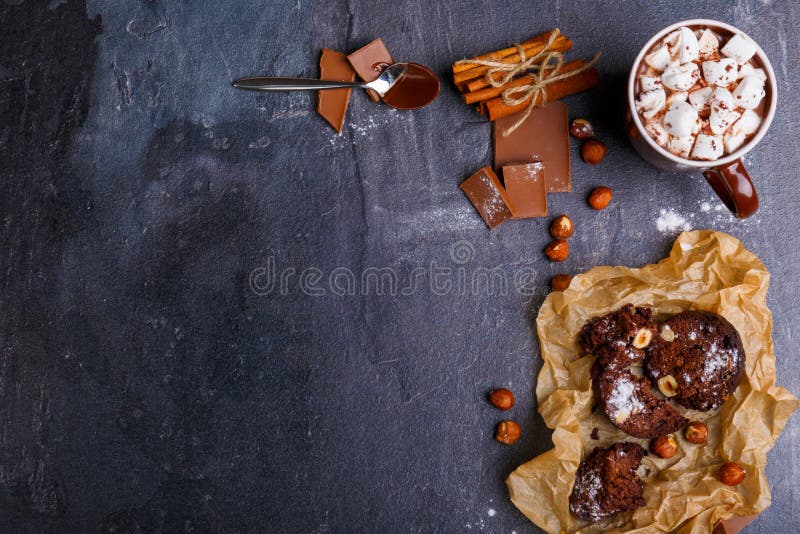 Une tasse de guimauve en chocolat, bâtons de cannelle, cuillères en chocolat, gâteau et noisettes Vue de ci-avant photo stock Une tasse de guimauve en chocolat, bâtons de cannelle, cuillères en chocolat, gâteau et noisettes Vue de ci-avant photo stock