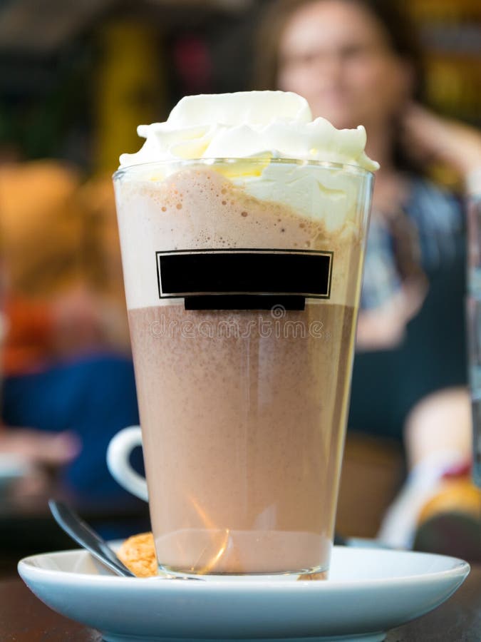 Une tasse de milk-shake, avec du chocolat et la crème fouettée, a servi dans un verre transparent, placé sur une soucoupe avec photographie stock libre de droits Une tasse de milk-shake, avec du chocolat et la crème fouettée, a servi dans un verre transparent, placé sur une soucoupe avec photographie stock libre de droits