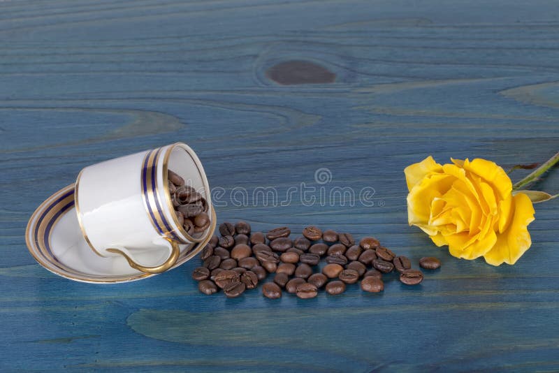 Une tasse pleine des grains de café entrebâillés avec des grains de café tombant sur un b images libres de droits Une tasse pleine des grains de café entrebâillés avec des grains de café tombant sur un b images libres de droits