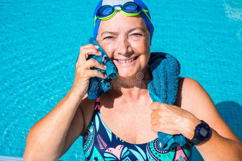 femme avec un bonnet de bain à fleurs qui rie dans une piscine Photos