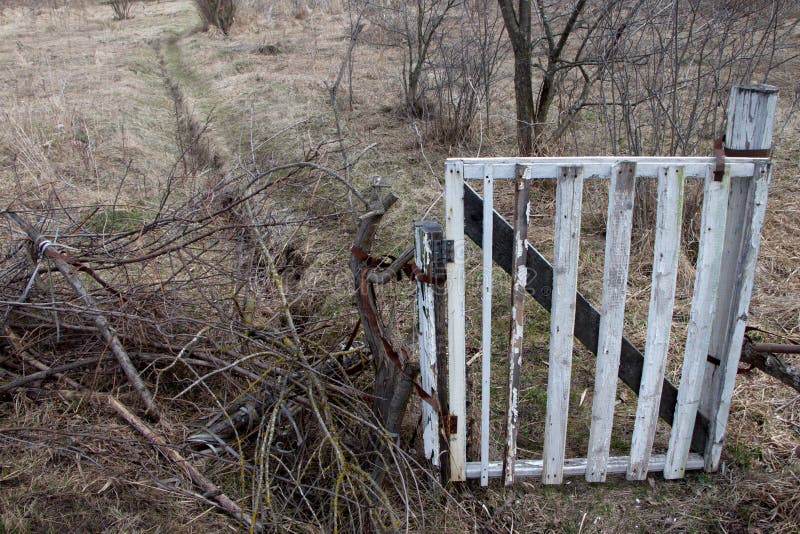 Une vieille porte blanche ferme l'entrée le long d'une route de campagne de saleté, deux voies dans le domaine images stock Une vieille porte blanche ferme l'entrée le long d'une route de campagne de saleté, deux voies dans le domaine images stock