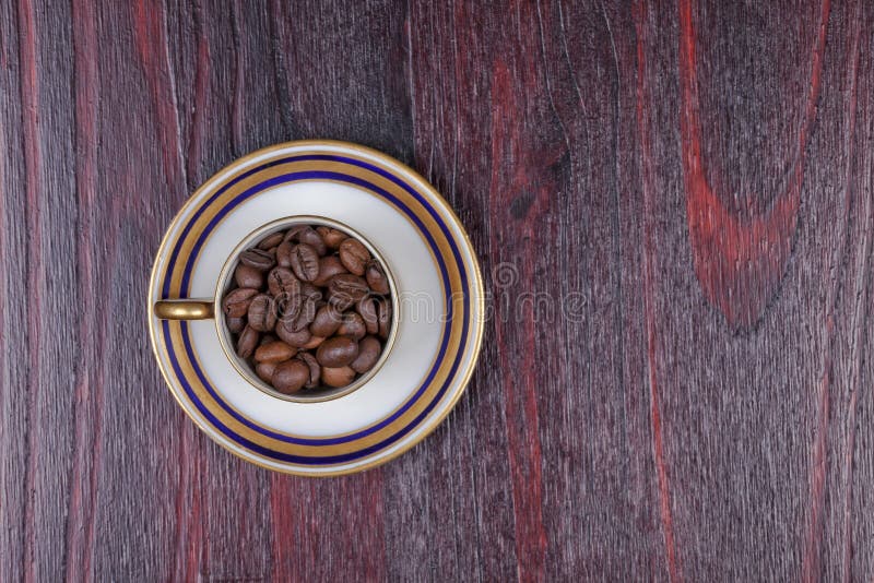 Une vieille tasse pleine des grains de café avec son plat photo stock Une vieille tasse pleine des grains de café avec son plat photo stock