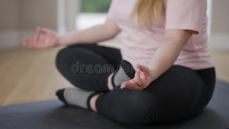 Unerkennbar mollig kaukasischen Frau sitzt in Lotus Pose auf Übungsmatte ein-und ausatmen. junger Plussize-Yogi