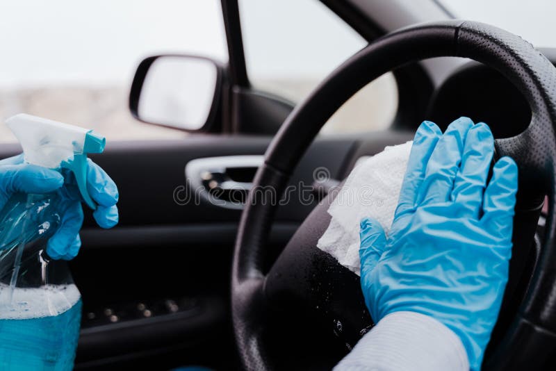 Unerkennbarer Mann in einem Auto mithilfe des Alkoholgels des Lenkrads während des Pandemie Coronavirus covid19 zu desinfizierende