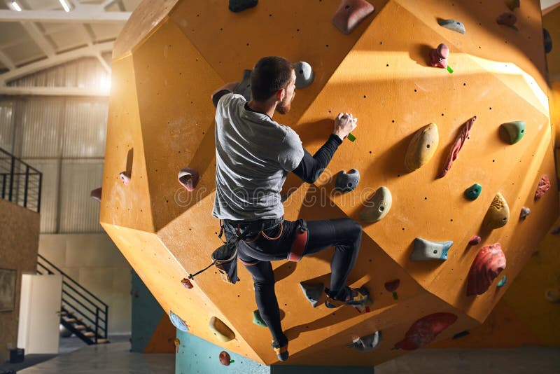 Unerkennbarer Sportler ohne Vorarm-Felsklettern an gelber Wand stockfotografie Unerkennbarer Sportler ohne Vorarm-Felsklettern an gelber Wand stockfotografie