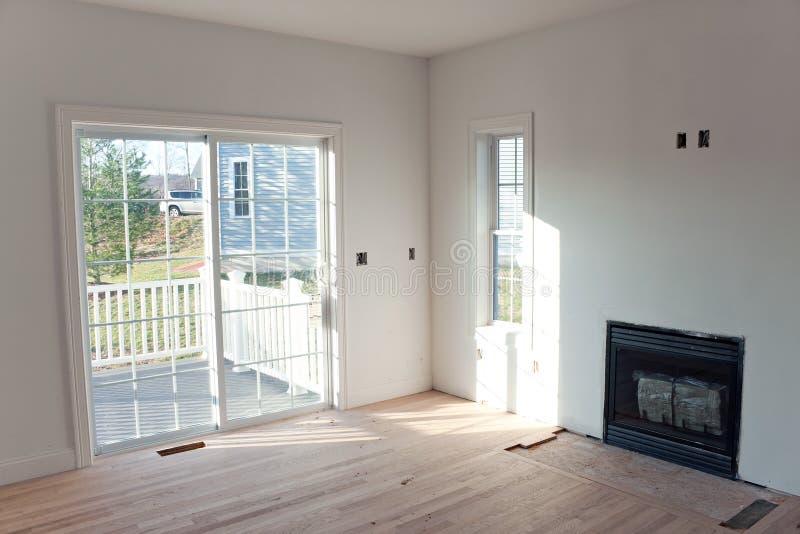 Modern home interior with sliding glass doors leading to a small porch and an unfinished gas fireplace log insert in the wall. Modern home interior with sliding glass doors leading to a small porch and an unfinished gas fireplace log insert in the wall.