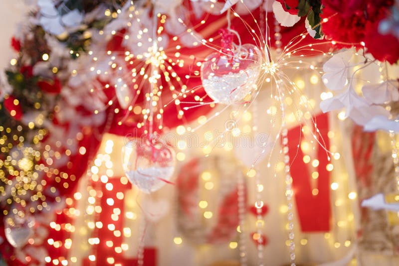 Unfocused shot of 14 February Valentines Day background. Shiny sparkling garland lights, flowers, hearts and bokeh.