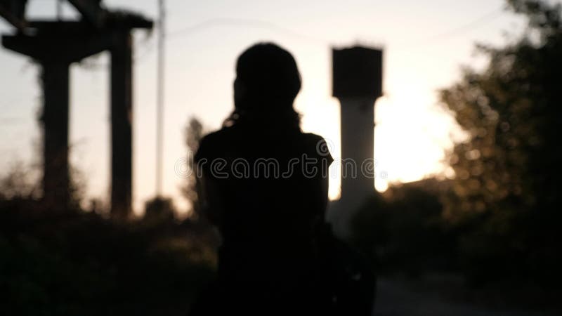 Unfocused silhouet van een jonge vrouw, die in de zonsondergang weggaan