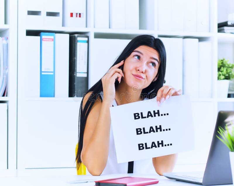 Effective communication concept. Young businesswoman in the process of useless conversation with the client or boss. Girl holds a piece of paper with the inscription blah blah denoting a waste of time talking on the phone. Effective communication concept. Young businesswoman in the process of useless conversation with the client or boss. Girl holds a piece of paper with the inscription blah blah denoting a waste of time talking on the phone.