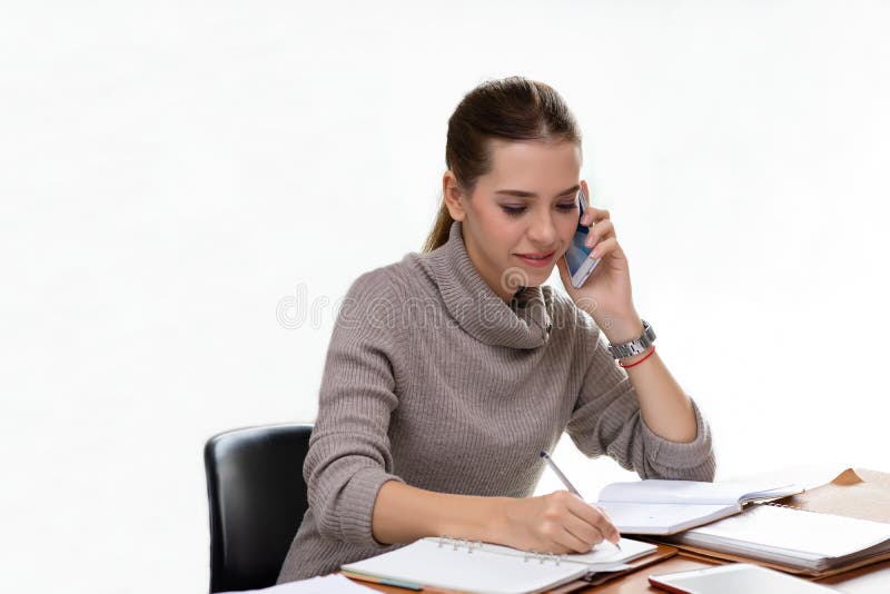 Ung affärskvinna på arbete som talar på telefonen och tar anmärkningar royaltyfria foton Ung affärskvinna på arbete som talar på telefonen och tar anmärkningar royaltyfria foton