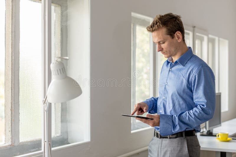 Ung affärsman som bläddrar internet på den digitala minnestavlan arkivbild Ung affärsman som bläddrar internet på den digitala minnestavlan arkivbild
