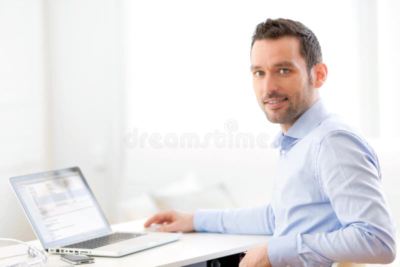 Ung affärsman som hemma arbetar på hans bärbar dator