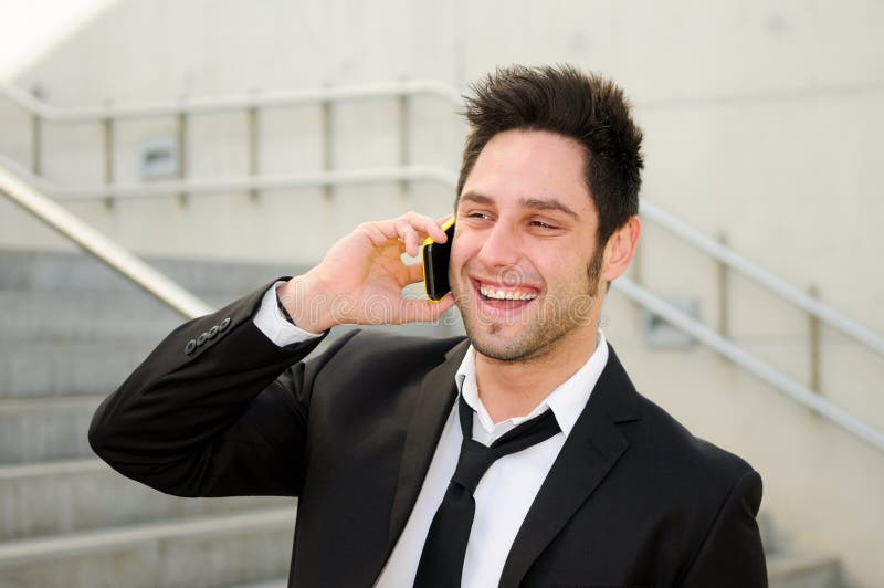 Ung affärsman som ler och talar på telefonen arkivfoto Ung affärsman som ler och talar på telefonen arkivfoto