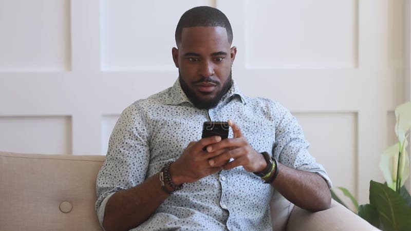 Ung afrikansk amerikan som ser mobilskärm arkivfilmer