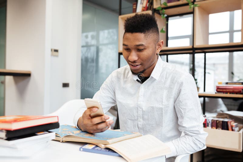 Ung afrikansk student i arkiv som pratar vid hans telefon arkivbilder Ung afrikansk student i arkiv som pratar vid hans telefon arkivbilder