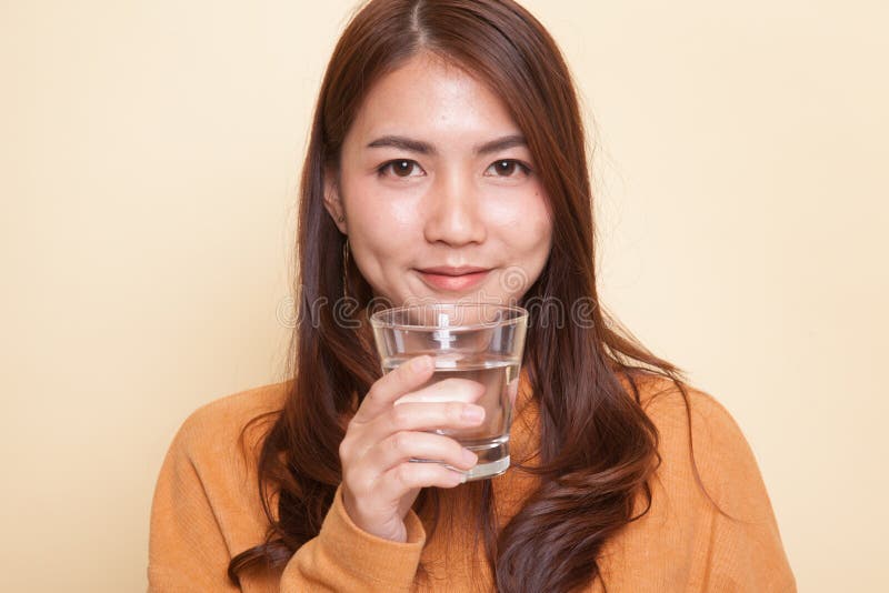 Ung asiatisk kvinna med ett exponeringsglas av dricksvatten