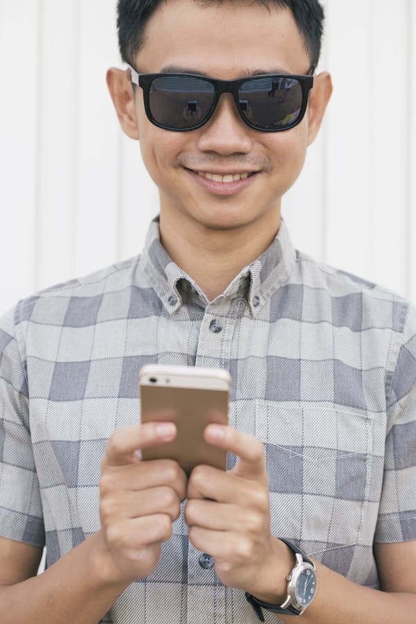 Ung asiatisk man som använder smartphonen royaltyfri foto Ung asiatisk man som använder smartphonen royaltyfri foto