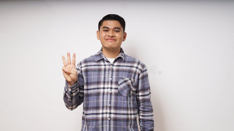 Young Asian man showing happy face expression while giving three fingers sign. Young Asian man showing happy face expression while giving three fingers sign