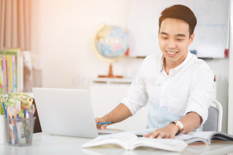 Ung asiatisk manuniversitetsstudent som arbetar med bärbar datordatoren fotografering för bildbyråer Ung asiatisk manuniversitetsstudent som arbetar med bärbar datordatoren fotografering för bildbyråer