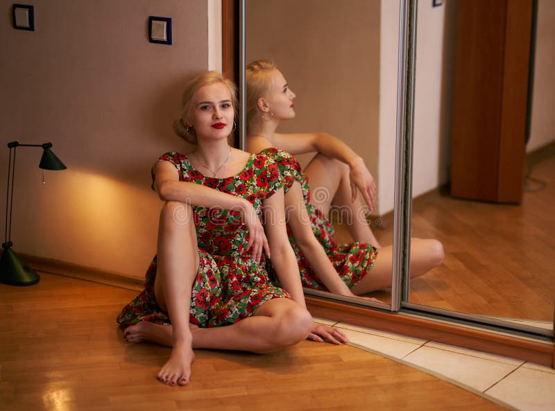 Ung attraktiv blond kvinna som poserar sammanträde på golvet i ett hotell nära spegeln royaltyfri fotografi Ung attraktiv blond kvinna som poserar sammanträde på golvet i ett hotell nära spegeln royaltyfri fotografi