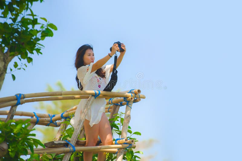 Ung attraktiv fotografkvinna som tar selfiefotoståenden med reflexkameran av det härliga landskapet med trädvegetation a royaltyfria foton Ung attraktiv fotografkvinna som tar selfiefotoståenden med reflexkameran av det härliga landskapet med trädvegetation a royaltyfria foton