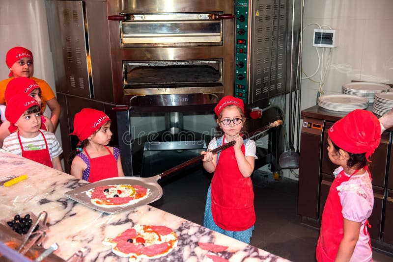 Young pizza bakers. Children learn to bake a pizza. Young pizza bakers. Children learn to bake a pizza