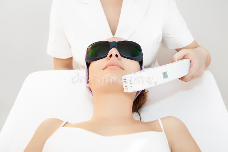 Young woman receiving epilation laser treatment in salon. Young woman receiving epilation laser treatment in salon