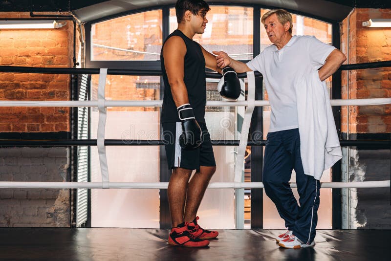Ung boxare som talar med hans mogna instruktör arkivfoton Ung boxare som talar med hans mogna instruktör arkivfoton