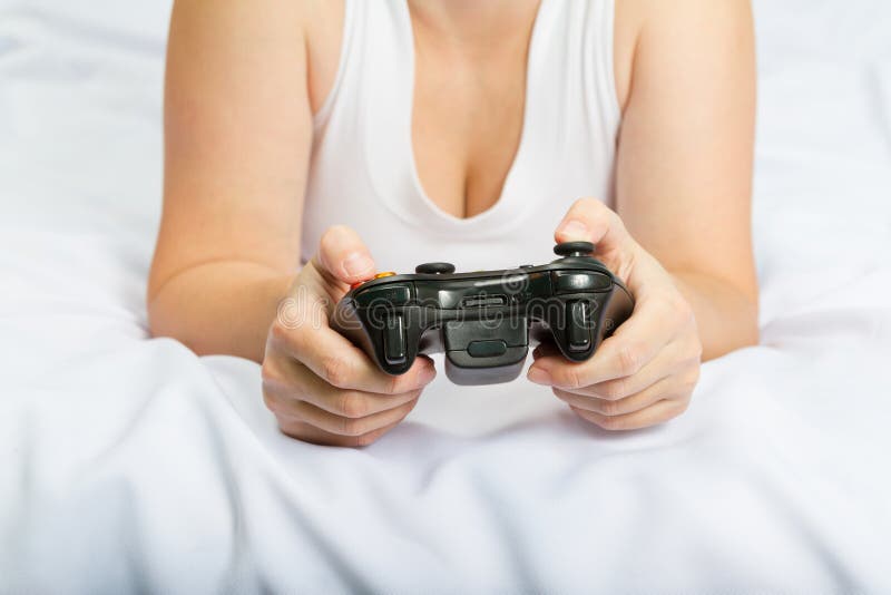Ung caucasian kvinna som spelar videospelkonsolen på sängen royaltyfri fotografi Ung caucasian kvinna som spelar videospelkonsolen på sängen royaltyfri fotografi