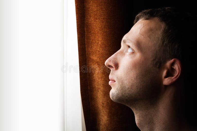 Ung Caucasian man som ser i ljust fönster royaltyfria bilder Ung Caucasian man som ser i ljust fönster royaltyfria bilder