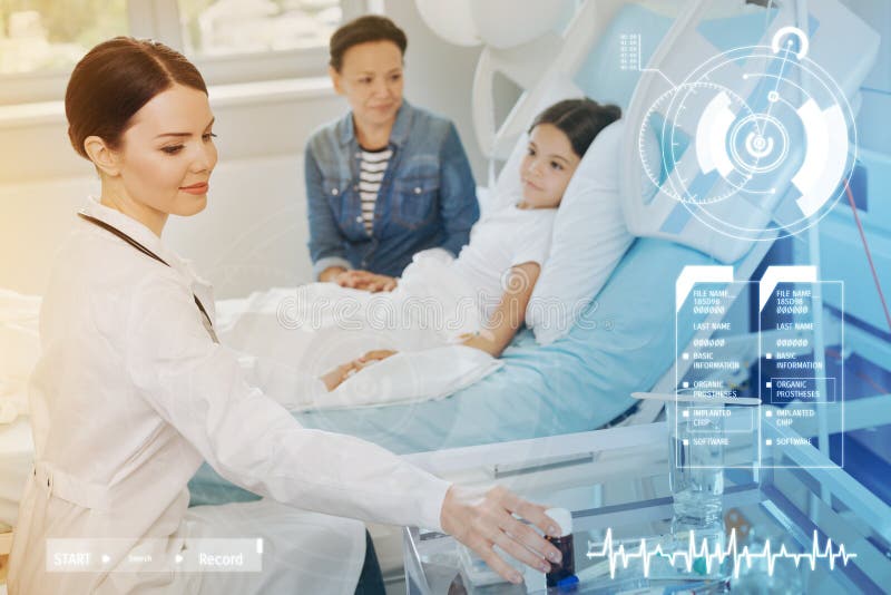 Ung doktor som ler, medan ta en flaska med piller från tabellen royaltyfria bilder Ung doktor som ler, medan ta en flaska med piller från tabellen royaltyfria bilder