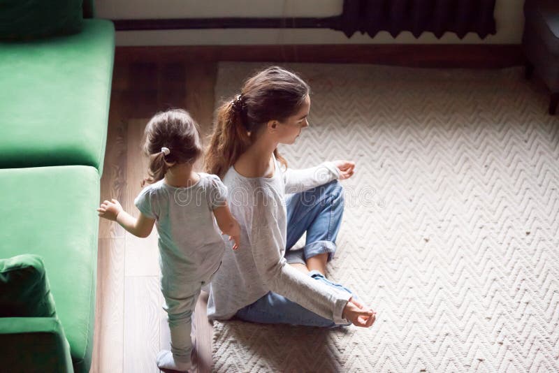 Ung ensamstående mamma som gör att spela för dotter för yogaövningsstund royaltyfria bilder Ung ensamstående mamma som gör att spela för dotter för yogaövningsstund royaltyfria bilder