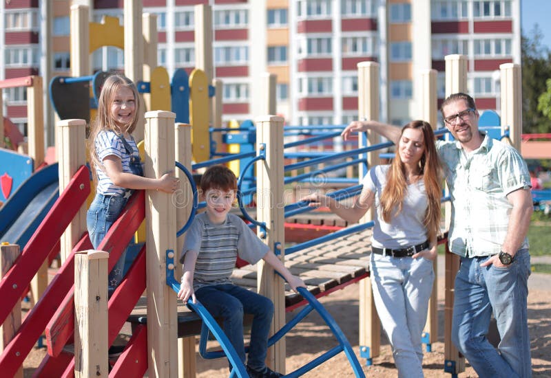 Ung familj med barn som har gyckel på lekplatsen royaltyfria bilder Ung familj med barn som har gyckel på lekplatsen royaltyfria bilder