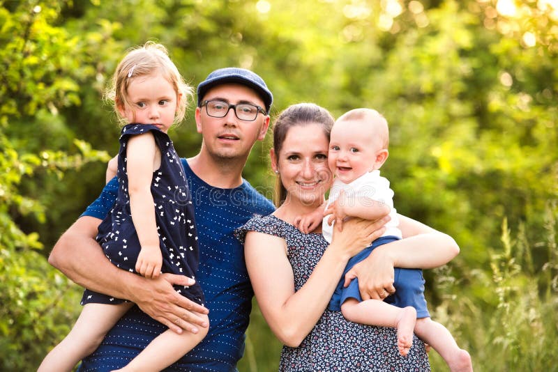 Ung familj med små barn i solig sommarnatur royaltyfria bilder Ung familj med små barn i solig sommarnatur royaltyfria bilder