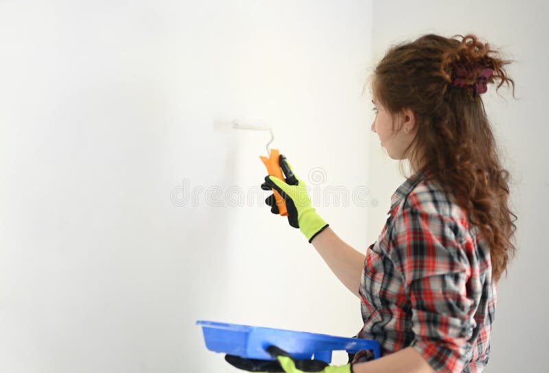 Ung flicka målar vita väggar arkivfoto