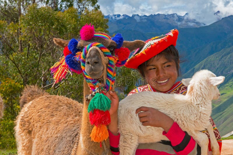 A young girl in Peru smiles while holding a llama and a lamb. The beautiful and pretty Peruvian young woman wears traditional clothes and dress from her culture. South America is a popular travel destination for people on vacation or holiday. A young girl in Peru smiles while holding a llama and a lamb. The beautiful and pretty Peruvian young woman wears traditional clothes and dress from her culture. South America is a popular travel destination for people on vacation or holiday.