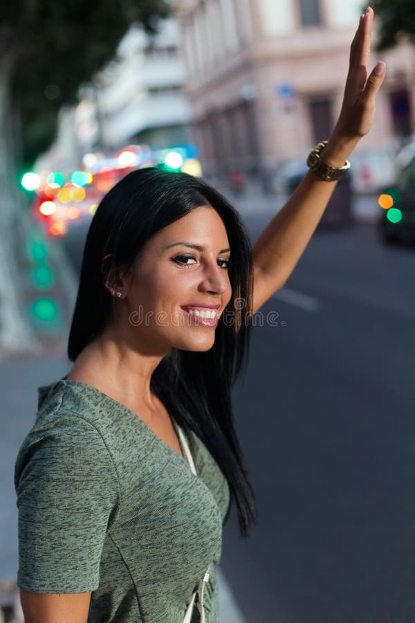 Ung flicka som kallar en taxi i staden på natten royaltyfri fotografi Ung flicka som kallar en taxi i staden på natten royaltyfri fotografi